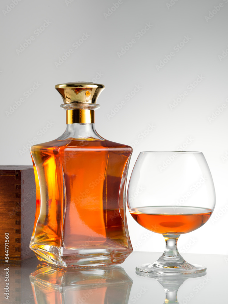 close up view of bottle of whiskey and a glass aside on grey back. close up view of bottle of whiskey and a glass aside on grey back.