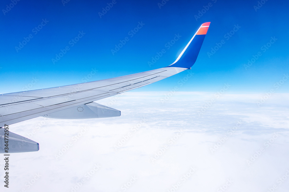 Fototapeta premium wing of airplane in the sky red winglet blue sky clouds