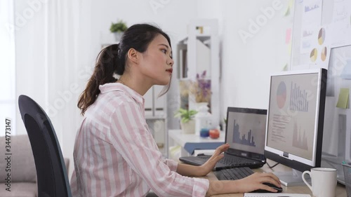 taiwanese female manager analyzing financial performance of company on computer and marking down briefly on paper. portrait of asian lady working from home studio.