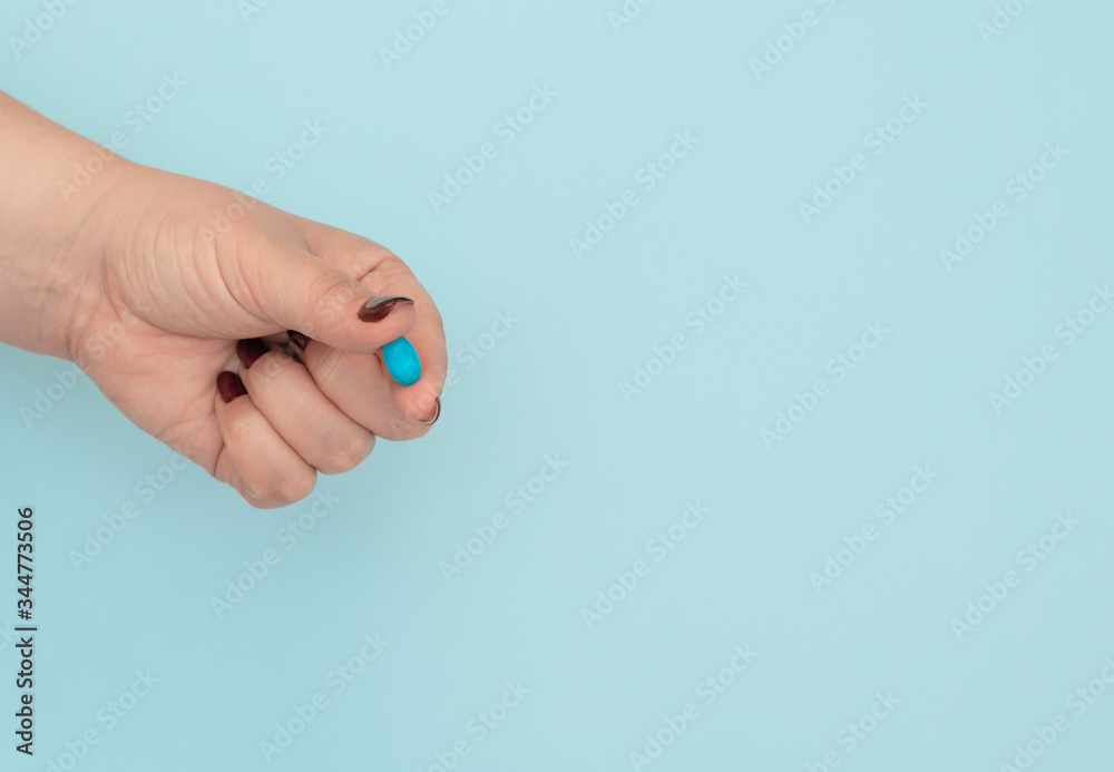 Blue pill on female hand on blue background. Seasonal diseases. Right choice, medicine concept. Flat lay style with copy space, top view. Blue pill on female hand on blue background. Seasonal diseases. Right choice, medicine concept. Flat lay style with copy space, top view.