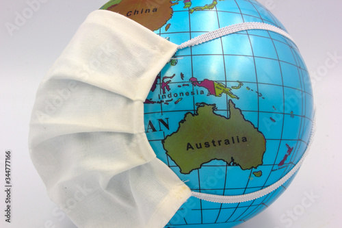 world earth globe focused on Australia and new Zealand with medical surgical face mask to combat corona virus covid 19