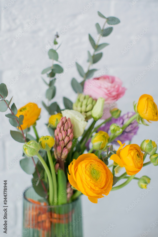 Beautiful bouquet with orange and pink ranunculus flowers, eucalyptus and hyacinth in a green vase