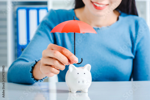 Young asian woman hand hold umbrella toy to protect the home and money for saving money and house and real estate property protection concept.