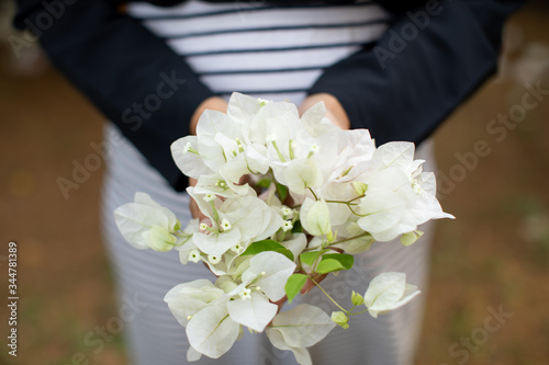 Valokuva a lady hold a bunch of white bougainvillaea