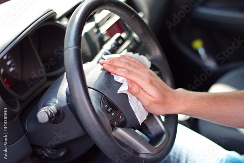 Man's hand cleaning steering wheel against virus with wet wipe © Vedrana