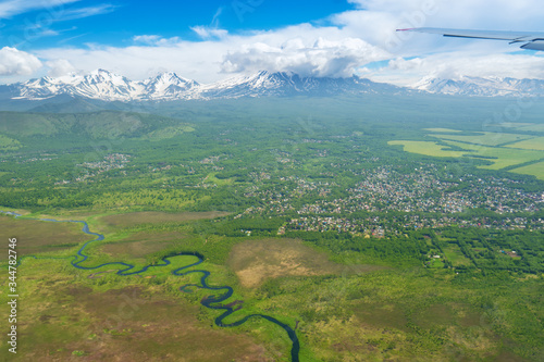 Russia. Kamchatka peninsula. The view from the porthole of the aircraft on the snowy peaks of volcanoes. winding river. residential areas of the city of Petropavlovsk-Kamchatsky.