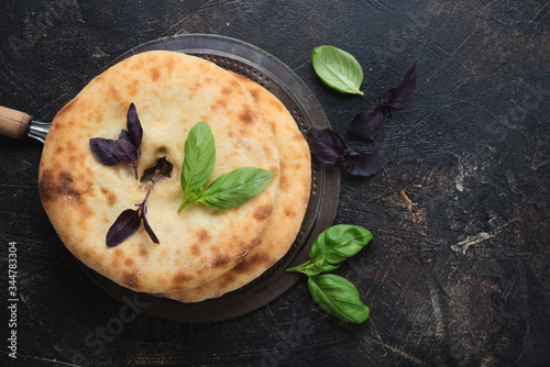 Freshly baked ossetian pies with meat stuffing on a dark brown stone background, horizontal shot with space, view from above photo