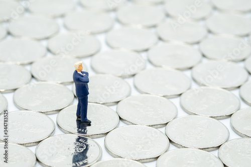 Money, Financial,Saving, Business Growth concept, Closeup of businessman miniature people figures stand on  silver coins on white table with copy space for text.