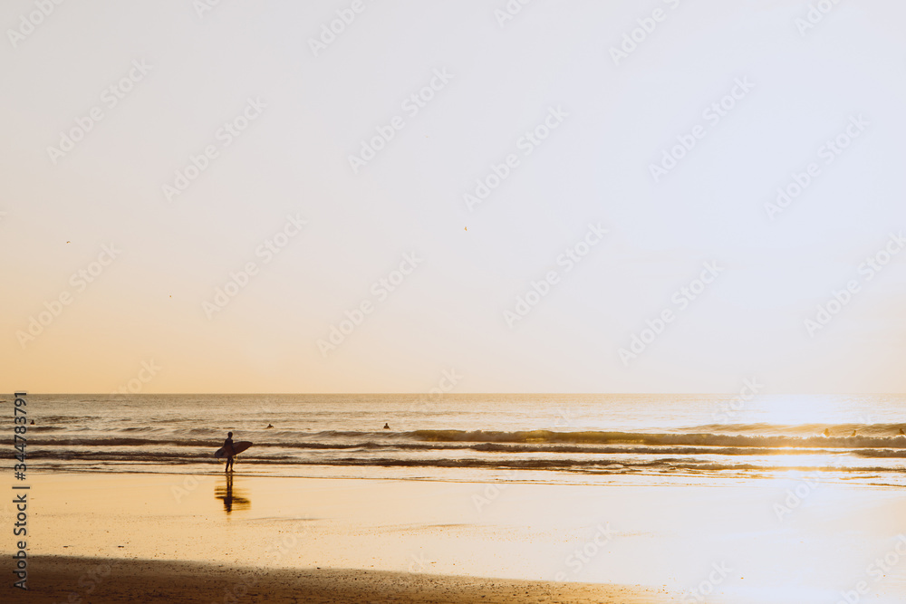 Ocean sunset, surfer backlit silhouette, warm orange colour