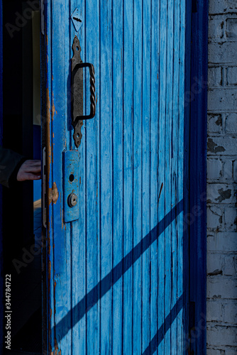 old wooden door with lock. Open blue door with damaged lock and ornate vintage handle © Ninel