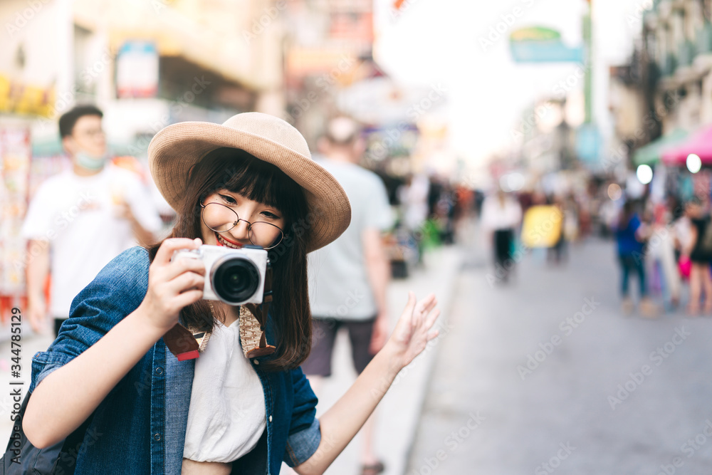 Young asian woman traveller take a photo by camera at khaosan street road.