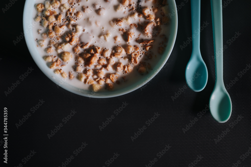 Blue bowl with musli and milk and two little blue spoons on grey background as a healthy breakfast Blue bowl with musli and milk and two little blue spoons on grey background as a healthy breakfast