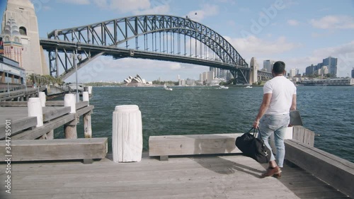 Man Walks in Awe on Wharf by Sydney Harbour Bridge. Tracking Wide Shot photo