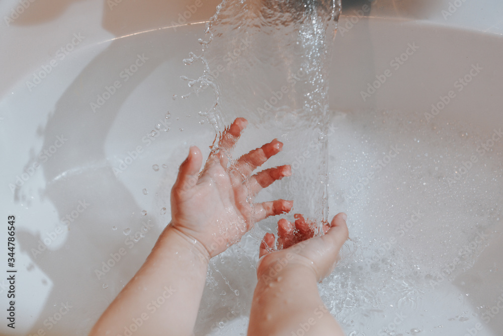 Cute little toddler girl washing her hands in a bathroom. Hygiene concept showing prevention of infection and viruses such as flu and covid-19 Cute little toddler girl washing her hands in a bathroom. Hygiene concept showing prevention of infection and viruses such as flu and covid-19