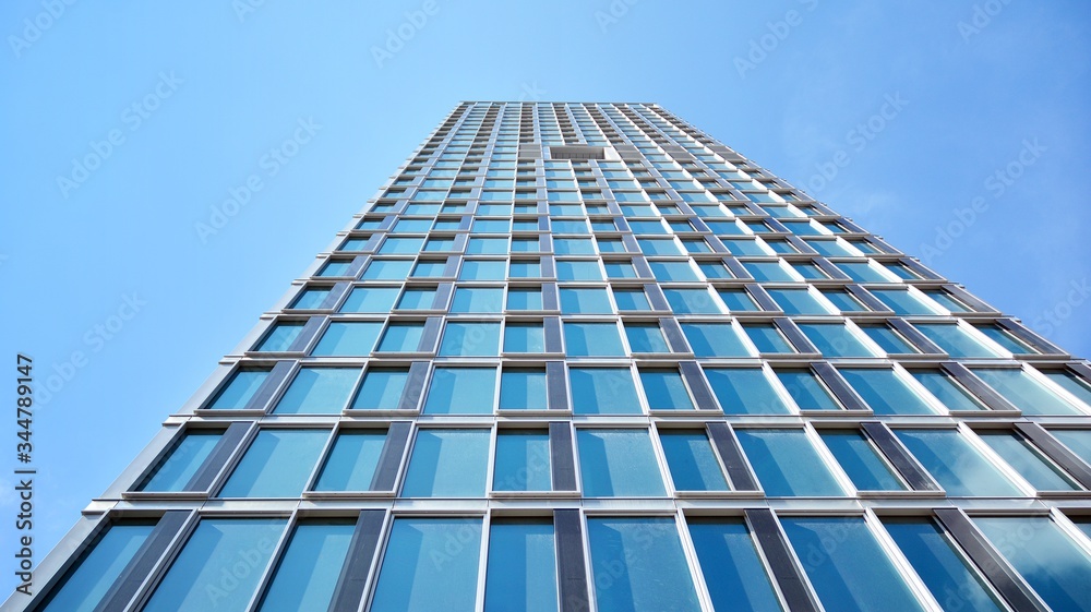Structural glass wall reflecting blue sky. Abstract modern architecture fragment. View of a modern glass skyscraper, modern office building. Modern office facade fragment with blue glass. Structural glass wall reflecting blue sky. Abstract modern architecture fragment. View of a modern glass skyscraper, modern office building. Modern office facade fragment with blue glass.