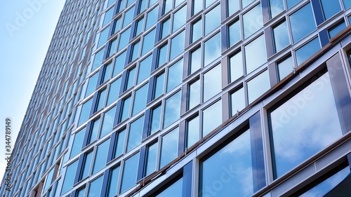 Structural glass wall reflecting blue sky. Abstract modern architecture fragment. View of a modern glass skyscraper  modern office building. Modern office facade fragment with blue glass.