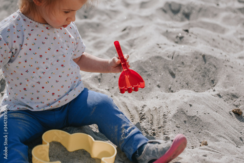 Schilderij op canvas Little girl playing in the sand with boxes and sand shovel