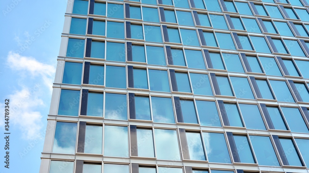 Structural glass wall reflecting blue sky. Abstract modern architecture fragment. View of a modern glass skyscraper, modern office building. Modern office facade fragment with blue glass. Structural glass wall reflecting blue sky. Abstract modern architecture fragment. View of a modern glass skyscraper, modern office building. Modern office facade fragment with blue glass.