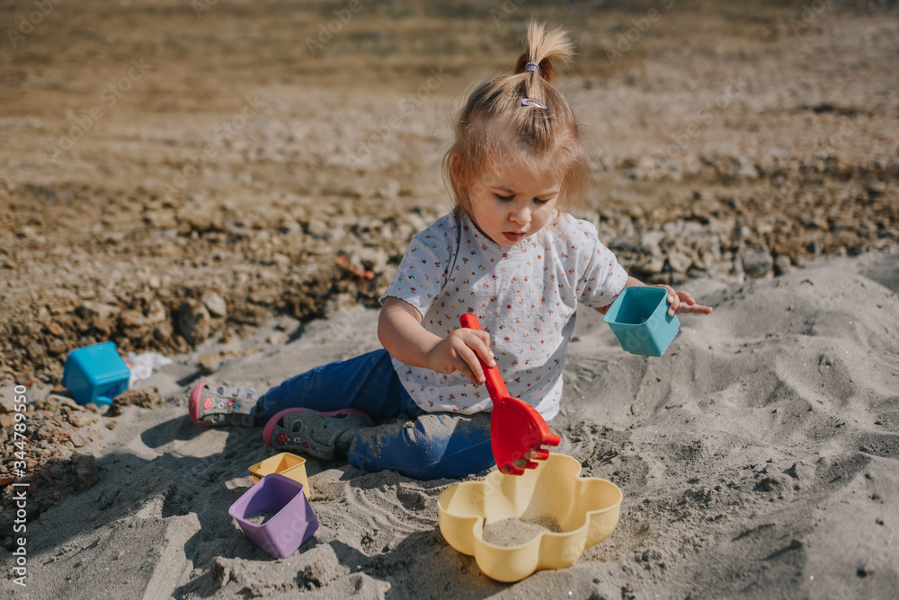 Portrait of little toddler girl playing in the sand with boxes and sand shovel Portrait of little toddler girl playing in the sand with boxes and sand shovel