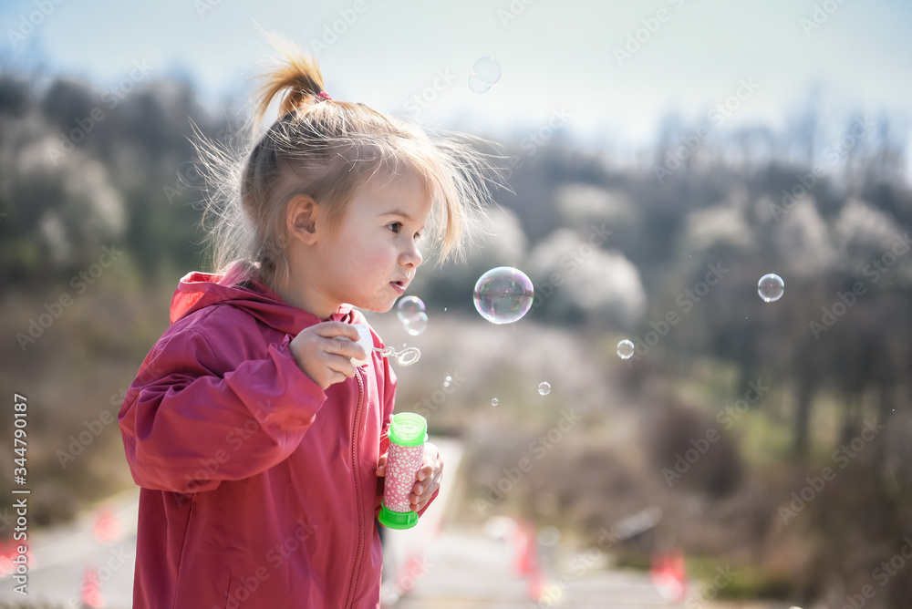 Two years old caucasian child girl blowing soap bubbles outdoor during a day - happy carefree childhood Two years old caucasian child girl blowing soap bubbles outdoor during a day - happy carefree childhood