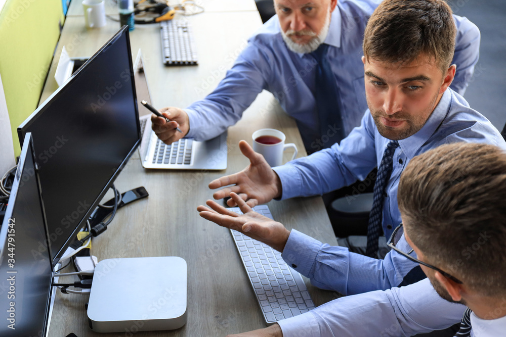 Group of young business men in formalwear working using computers while sitting in the office. Group of young business men in formalwear working using computers while sitting in the office.