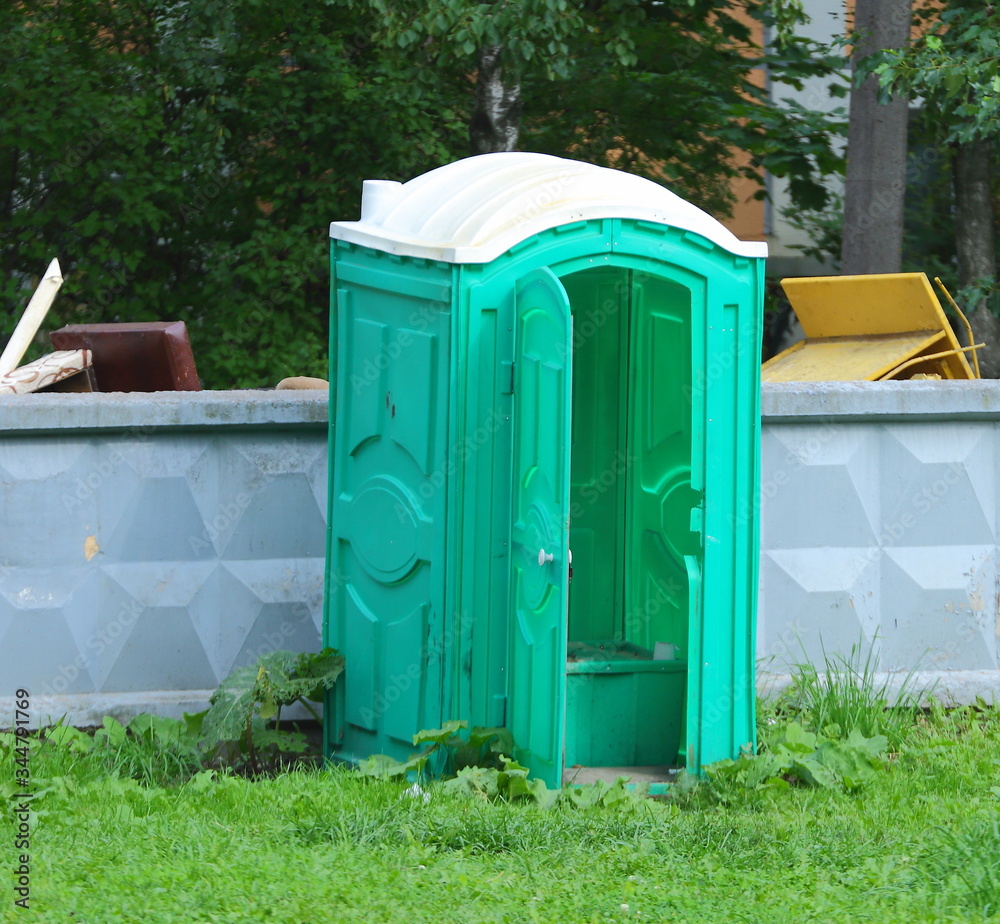 Mobile green composting toilet at gray concrete fence Mobile green composting toilet at gray concrete fence