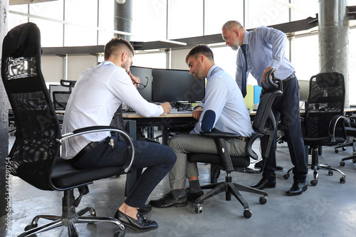 Group of modern business men in formalwear analyzing stock market data while working in the office. © ty