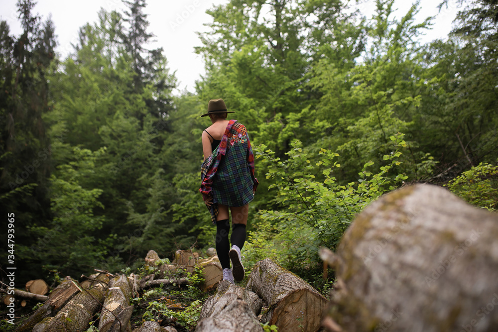 A girl in a brown hat walks through the beautiful forest on her feet, her favorite gym shoes, she enjoys nature and relaxes from everyday routine. She loves to walk in the mountains A girl in a brown hat walks through the beautiful forest on her feet, her favorite gym shoes, she enjoys nature and relaxes from everyday routine. She loves to walk in the mountains