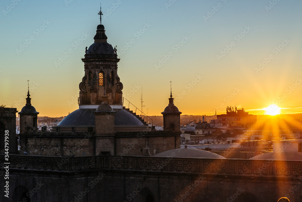 Sunset in Seville with orange rays illuminating the city.