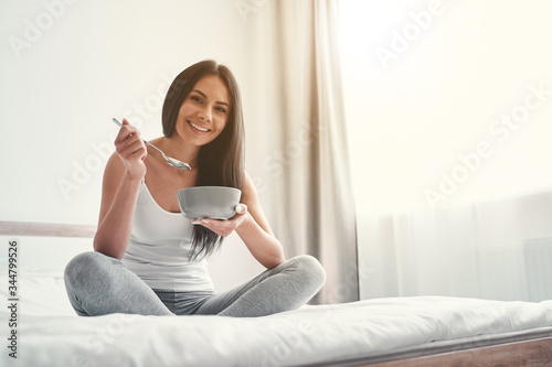 Happy female person having her breakfast in bedroom photo