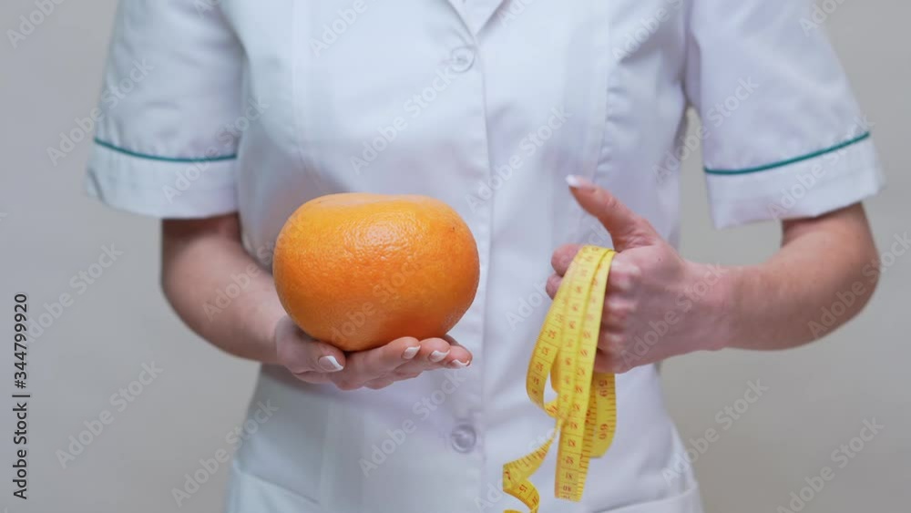 nutritionist doctor healthy lifestyle concept - holding organic grapefruit fruit and measuring tape nutritionist doctor healthy lifestyle concept - holding organic grapefruit fruit and measuring tape