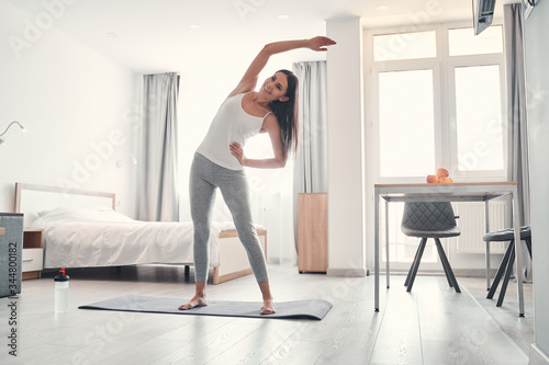 Positive delighted young woman doing morning exercise photo