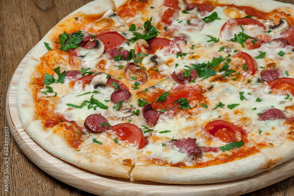 pizza on a wooden tray stands on a wooden table pizza on a wooden tray stands on a wooden table