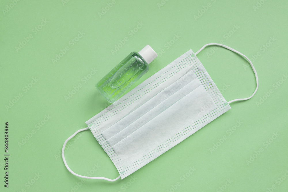 medical mask and sanitizer on green background. Stay home hygienic quarantine concept. Flat lay, top view medical mask and sanitizer on green background. Stay home hygienic quarantine concept. Flat lay, top view