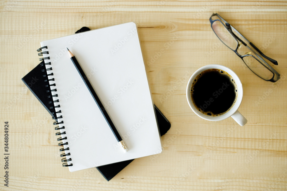 cup of hot coffee on wooden background with notebook. Work from home concept. cup of hot coffee on wooden background with notebook. Work from home concept.