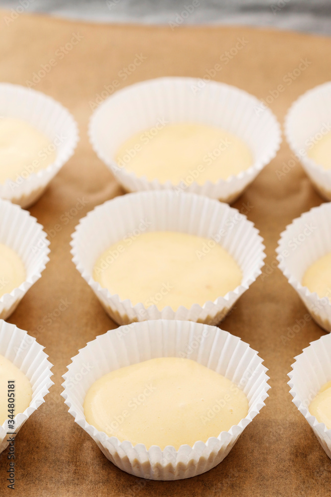 Cupcake dough in paper molds. Sweets prepared for baking.