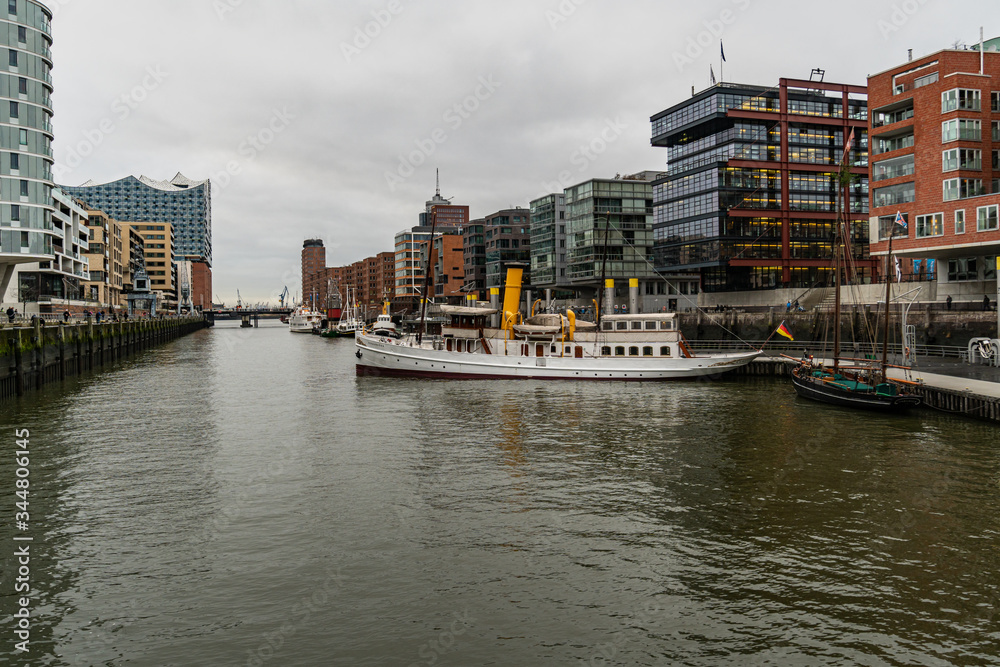 The Harbor District (HafenCity) in Hamburg, Germany. A view of the Sandtorkai with some old ships on a cloudy day with a dramatic sky.
