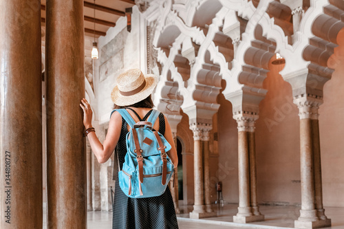 tourist girl walks through the old Moorish Palace of Aljaferia and admires the carved arches