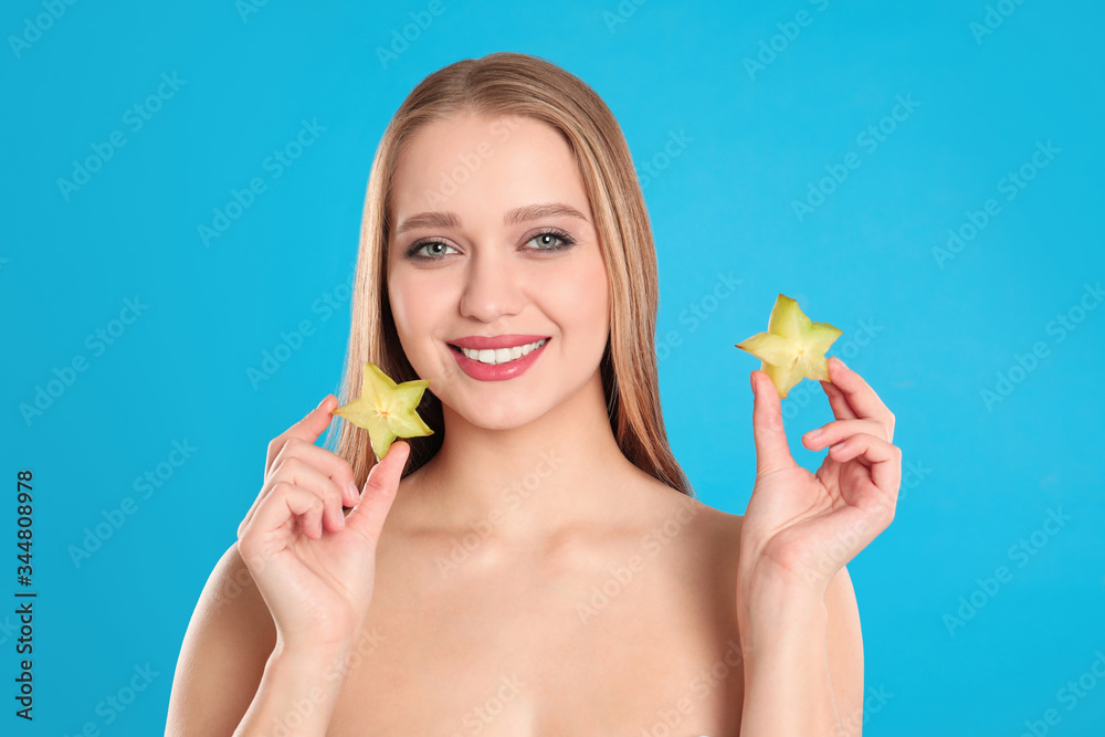 Young woman with cut carambola on blue background. Vitamin rich food Young woman with cut carambola on blue background. Vitamin rich food