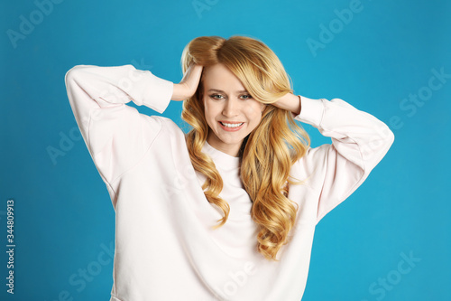 Portrait of beautiful young woman with dyed long hair on blue background