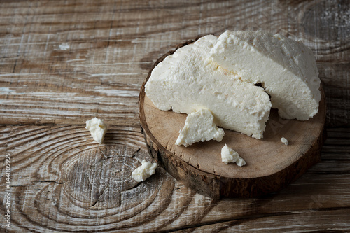 homemade Adyghe cheese cut into pieces on a wooden background