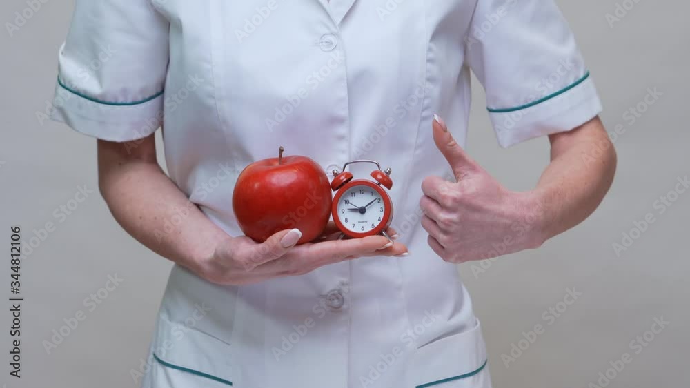 nutritionist doctor healthy lifestyle concept - holding organic red apple and alarm clock nutritionist doctor healthy lifestyle concept - holding organic red apple and alarm clock