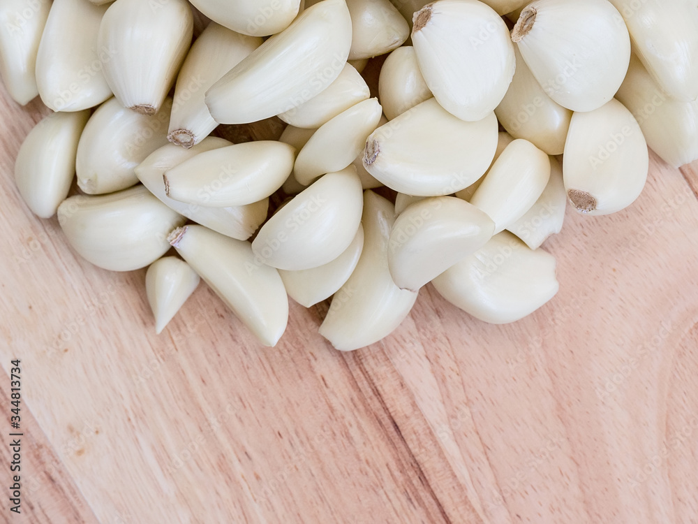 many peeled white cloves of garlic on a wooden cutting board. Copy space for text. many peeled white cloves of garlic on a wooden cutting board. Copy space for text.