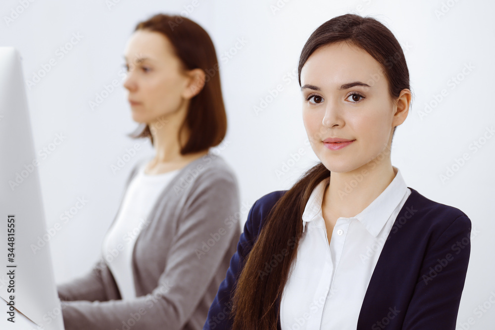 Business woman looking at camera at the background of working colleagues. Office life concept, headshot Business woman looking at camera at the background of working colleagues. Office life concept, headshot