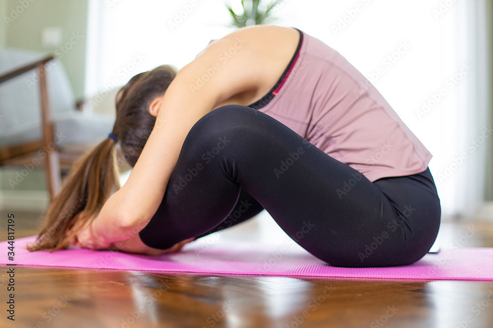 Yoga in living room - Sporty woman stretching legs on exercise mat Yoga in living room - Sporty woman stretching legs on exercise mat
