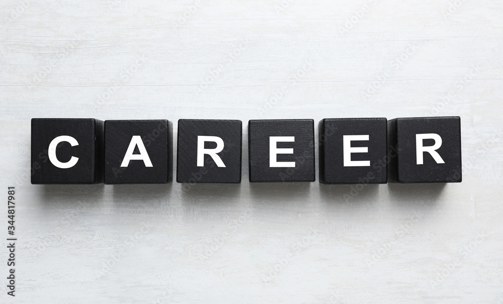 Obraz premium Black cubes with word CAREER on white wooden background, flat lay