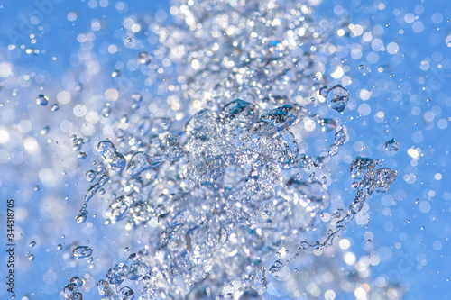 Water droplets spraying from a fountain in abstract design on blue sky background and detail and contrast. Concept.