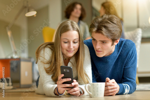 Young couple of students using smartphone at home