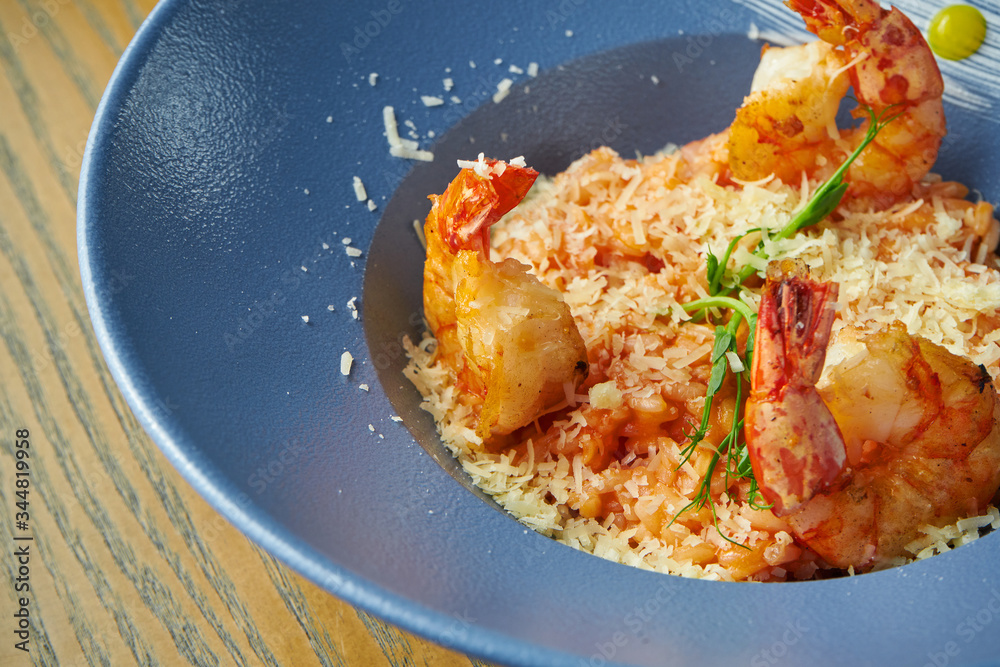 Risotto of rice with shrimps. Rice with seafood in a blue bowl against a wooden background. Italian cuisine Risotto of rice with shrimps. Rice with seafood in a blue bowl against a wooden background. Italian cuisine