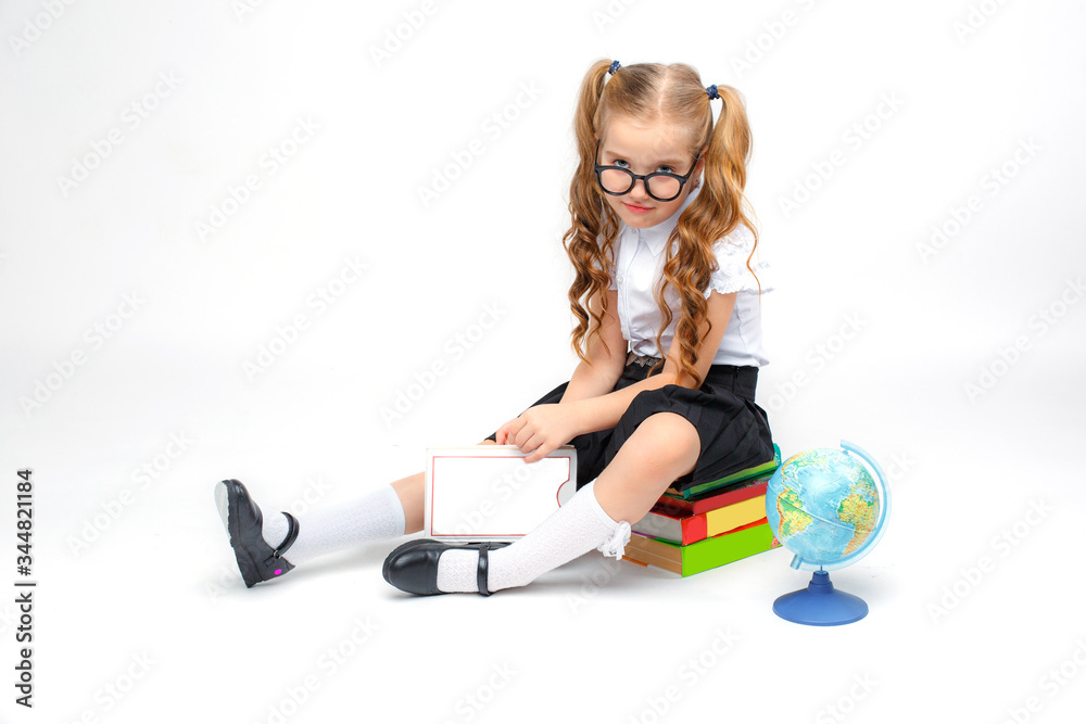 a little girl in school uniform and glasses holding a book in her hands sitting on a stack of books on a white background a little girl in school uniform and glasses holding a book in her hands sitting on a stack of books on a white background